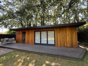 a small wooden cabin with a wooden deck at Oak Lodge in Hambledon