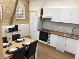 a kitchen with white cabinets and a table with chairs at Gîte 4 personnes in Brantôme