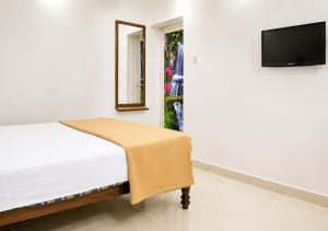 a bedroom with a bed and a tv on a wall at Aditi in Thekkady