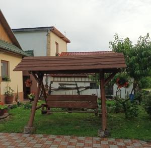a wooden pergola with a bench in a yard at Chalupa Za zeleným plotom in Pača
