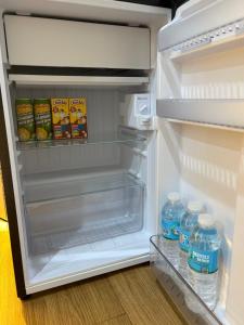 an open refrigerator with bottles of water and milk at DASIG Homes1 near airport, Bayanihan Flats 1 Condominium Mactan in Pajak