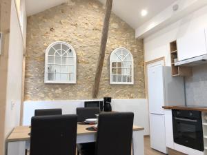 a kitchen with a table with chairs and a stone wall at Gîte 4 personnes in Brantôme