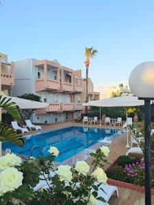 ein Schwimmbad mit weißen Liegestühlen und ein Hotel in der Unterkunft Toulipa Rooms in Agia Ermioni