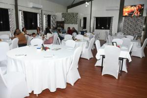 a banquet hall with white tables and white chairs at Standard - Bluelight Village Hotel in Nadi