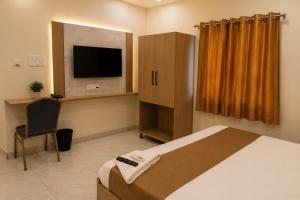 a bedroom with a bed and a tv and a chair at Hotel Vaarahi Chanda Nagar, Near Hitech City in Hyderabad
