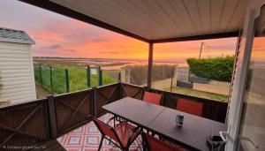 a balcony with a table and chairs and a sunset at Location Mobile home in Marseillan