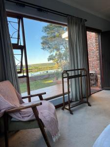 a bedroom with a large window with a bed and a chair at Riverfront Homestay in Port Elizabeth