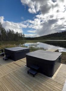 two tubs sitting on a dock next to a lake at Sāmeland Retreat, Mirrored Glass Cabins, Swedish Lapland in Arvidsjaur