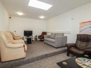 a living room with chairs and a couch and a tv at Newseal House in St Austell