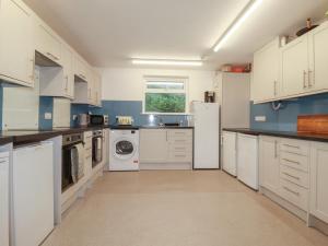 a kitchen with white cabinets and a washer and dryer at Newseal House in St Austell