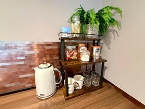 a coffee maker on a shelf with cups and a plant at Oak Lodge in Hambledon
