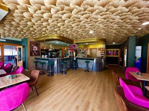 ein Restaurant mit rosa Stühlen und einer Bar in der Unterkunft Hotel Marola in A Lanzada