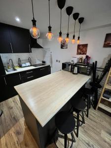 a kitchen with a wooden counter top and black cabinets at Cosy Private Bedrooms in Euston Station in London