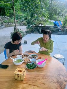 two women sitting at a wooden table eating food at May Lai Homestay in Tả Van