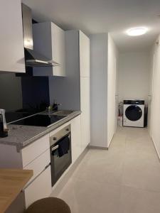a white kitchen with a sink and a microwave at Cosy studio dans un quartier animé et pittoresque in Fribourg
