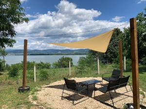 two chairs and a table under a tent with a lake at Brvnara Carpe Diem in Usije