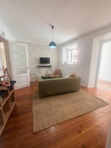 a living room with a green couch on a wooden floor at Bogage Boutique House in Setúbal +16 photos