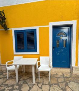 a table and chairs in front of a building with a blue door at Gregor Villa in Asim Zeneli