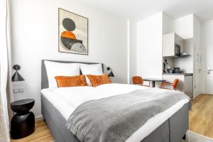 a white bedroom with a large bed with orange pillows at Global Living Chemnitz Rosenhof in Chemnitz
