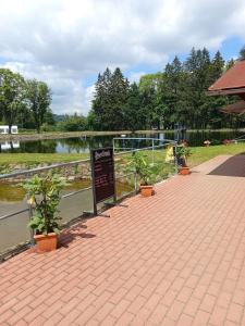 a sign on a brick walkway next to a lake at Zimmerův Statek in Mikulášovice