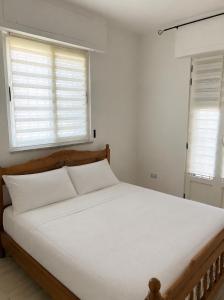 a bedroom with a bed with white sheets and two windows at Villa Keti in Velipojë +1 photo