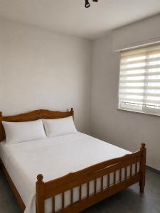 a bedroom with a bed with white sheets and a window at Villa Keti in Velipojë