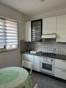 a kitchen with white cabinets and a stove and a table at Villa Keti in Velipojë
