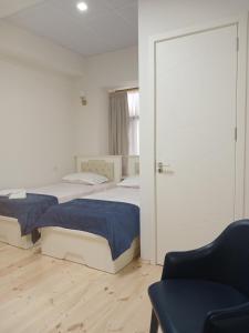 two beds in a room with a couch and a chair at Hotel White Neptun Georgia Tbilisi in Tbilisi City