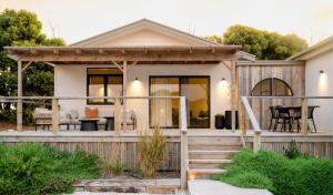 a house with a deck with a dining area at The Sanctuary at Bayside Glamping in Marion Bay
