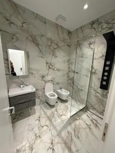 a marble bathroom with a toilet and a sink at Merlis Hotel in Kusarth