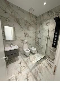 a marble bathroom with a toilet and a sink at Merlis Hotel in Kusarth