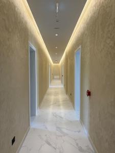 a hallway with a long corridor with white marble floors at Merlis Hotel in Kusarth