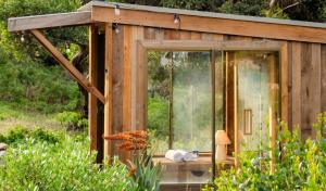 a wooden shed with a glass door in a garden at The Sanctuary at Bayside Glamping in Marion Bay