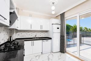 a kitchen with white cabinets and a large window at Villa Azalea 2 in Ortaca