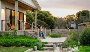 a woman sitting on the porch of a house at The Sanctuary at Bayside Glamping in Marion Bay