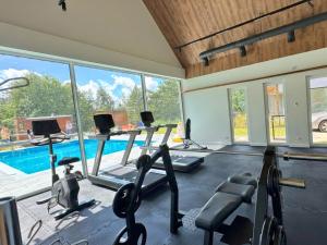 a gym with cardio equipment and a swimming pool at Domek Reset Kaszuby - Basen, Jacuzzi, Sauna, Siłownia in Łączyno