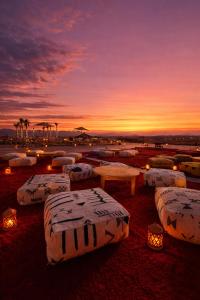 a group of beds with lights and a sunset in the background at Agafay Oryx Camp in Aït Mazou +2 photos
