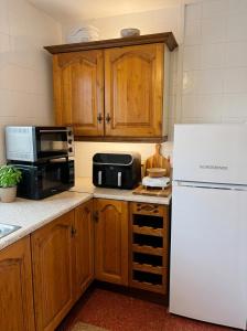 a kitchen with wooden cabinets and a white refrigerator at Jennys Bar in Mullagh