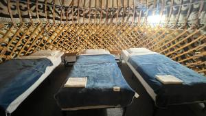 a room with three beds in a wooden wall at BooGoo yurt camp in Song-Kul