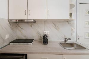 a kitchen with white cabinets and a sink and a counter at Kreka Apartments in Pefkochori +49 photos