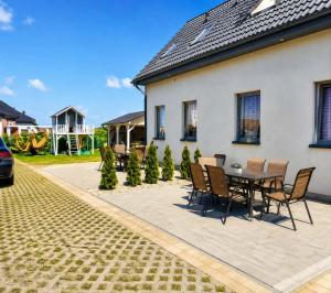 a patio with a table and chairs next to a house at Domki Osada Kalinowa Nowęcin Łeba Sauna in Łeba
