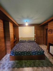 a bedroom with a bed in a room with wooden walls at Little Bro Mae Hong Son in Ban Mai