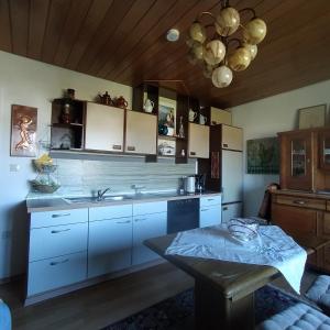 a kitchen with white cabinets and a table and a chandelier at Ferienwohnung im Krokusweg in Langenneufnach
