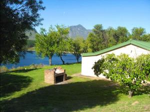a white building with a brick oven next to a lake at Korentepoort Dam in Riversdale