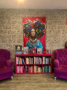 ein Bücherregal mit Büchern und ein Gemälde einer schwarzen Frau in der Unterkunft Hotel Marola in A Lanzada