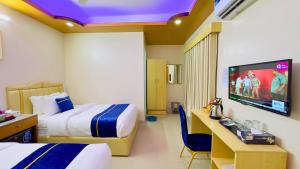 a hotel room with two beds and a flat screen tv at The Ambassador Hotel Dhaka in Dhaka