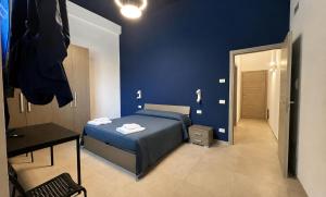 a blue bedroom with a bed and a desk at Affitta camere via Po in Porto SantʼElpidio