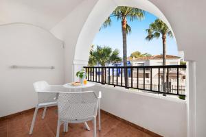 a balcony with a table and chairs and palm trees at Mac Puerto Marina Benalmádena in Benalmádena
