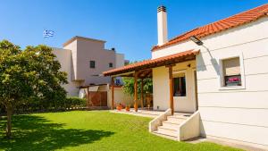 a white house with a grass yard at Isidoros House in Keramoti