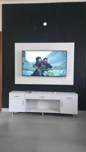 a flat screen tv sitting on top of a white entertainment center at 4j Aravalli Farms in Dhauj